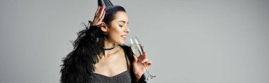 Stylish young woman in black dress holding champagne glass.