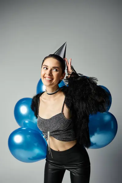 stock image A stylish young woman with short dyed hair celebrates with a party hat and a bunch of colorful balloons.