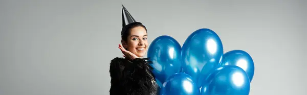 stock image A stylish young woman with short dyed hair poses with a bunch of blue balloons in a studio setting.