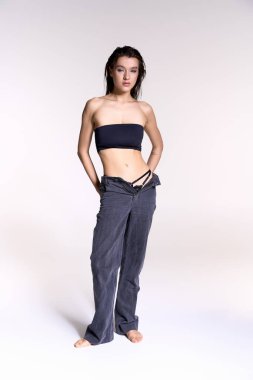 Young woman with wet hair in trendy strapless top and pants.