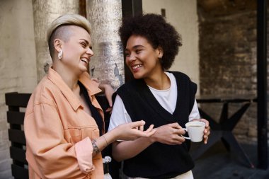 İki farklı, güzel kadın bir kafede sıcacık bir kucaklaşmanın tadını çıkarıyor..