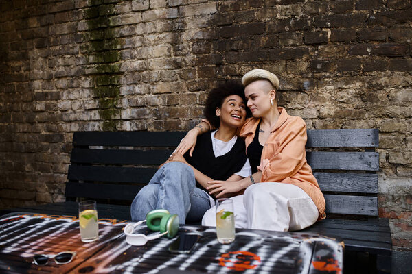 Two women embracing on a rustic wooden bench.