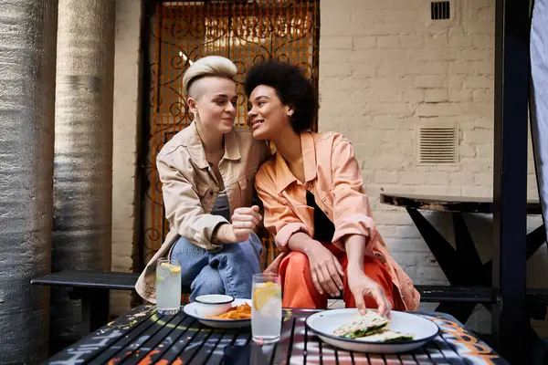 stock image Two women sitting closely together at a table, engaged in conversation and connection.