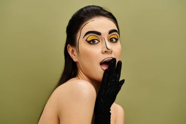 Çekici esmer bir kadın yüzüne pop sanat makyajı yapmış, parlak siyah eldivenler giymiş..