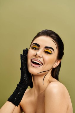 Güzel, esmer, pop sanatından esinlenilmiş sarı makyajlı, siyah eldivenli bir kadın..