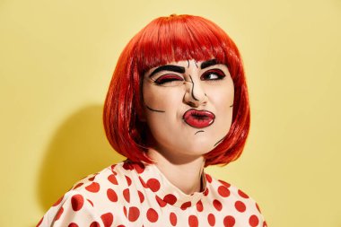 Yaratıcı pop sanat makyajlı, sarı arka planda benekli bluz giyen güzel bir kızıl saçlı..