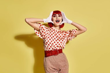 Sarı arka planda polka noktalı tişörtü olan kızıl saçlı güzel bir kadın çizgi romandaki karakteri andırıyor..