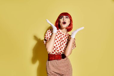 Beyaz eldivenli şık bir kızıl saç makyaj malzemesi sergiliyor, polka noktalı bluz giyiyor, parlak sarı bir arka plana karşı.