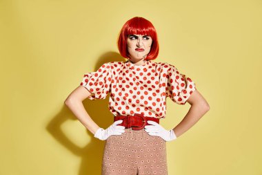 Vibrant red-haired woman with pop art makeup donning a polka dot blouse on a bold yellow backdrop. clipart