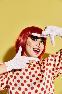 Dramatik pop sanat makyajı ve sarı arka planda benekli bluzu olan kızıl saçlı güzel bir kadın..