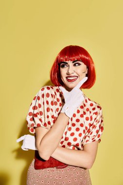 Göz kamaştırıcı bir kızıl saçlı pop sanat makyajıyla süslenmiş sarı bir fona karşı neşeli ve enerjik bir enerji yayıyor..