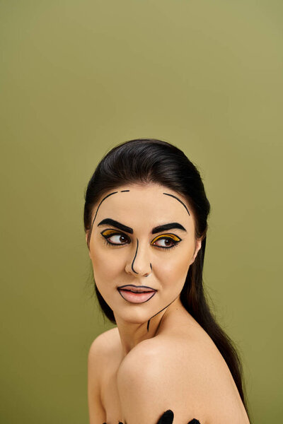 A pretty brunette woman wearing makeup resembling pop art, concealing her face with a fake mask and wearing black gloves.