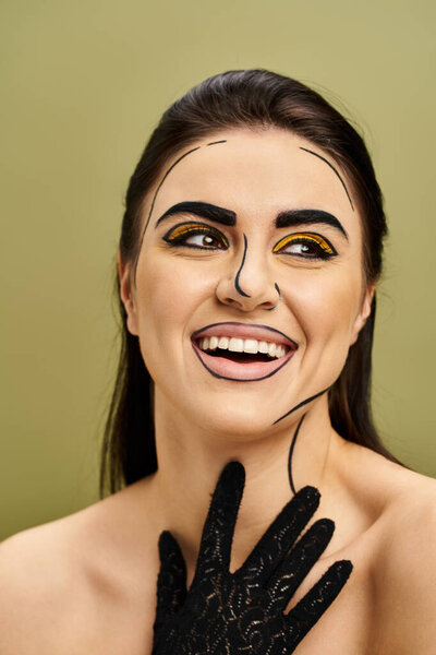 Brunette woman dons pop art makeup, black gloves, and a fake face.
