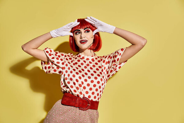 Красивая рыжая женщина в горошек топ и белые перчатки с творческим поп-арт макияж на желтом фоне.