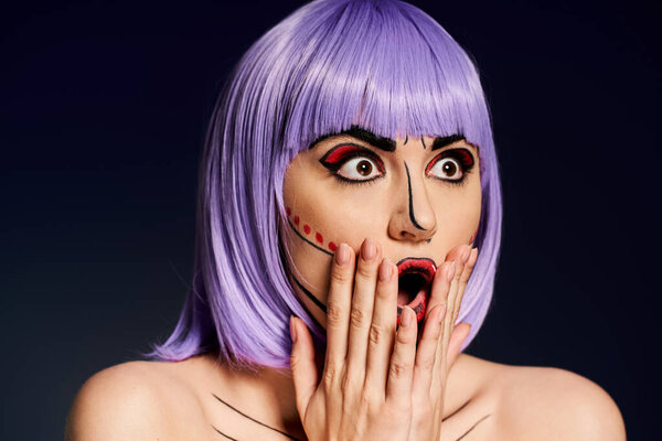 Женщина с фиолетовыми волосами и поп-арт макияж страстно держит руки к лицу на черном фоне.