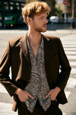 Şık giyinmiş kızıl saçlı genç adam şehrin köşesinde kendinden emin bir şekilde duruyor..