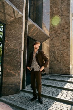 Red-haired young man in debonair suit walking up city steps. clipart