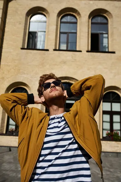 stock image Stylish man in yellow jacket stands confidently before a building.