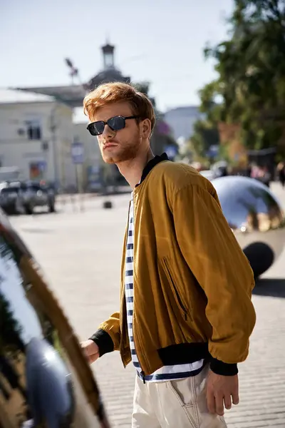 stock image Young man with red hair, wearing sunglasses and a tie, standing confidently next to an installation art.