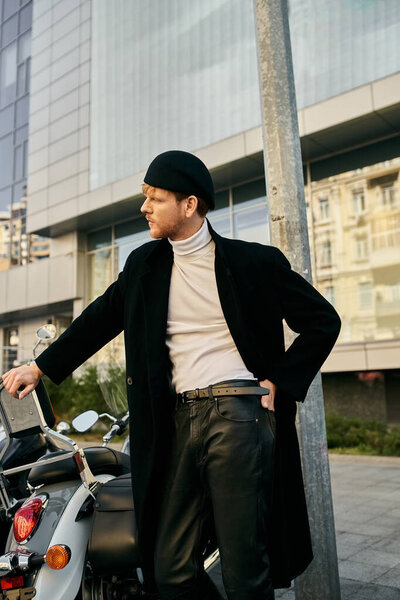 Молодой рыжеволосый мужчина в красивом костюме, уверенно стоящий рядом с припаркованным мотоциклом.