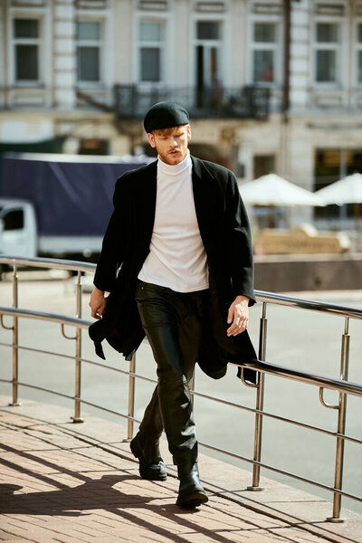 Стильный молодой человек с рыжими волосами прогуливается вдоль забора в городе.