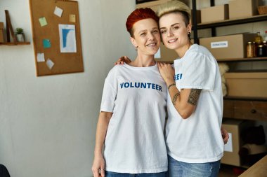 Gönüllü tişörtlü lezbiyen bir çift hayır işlerinde birlik olup takım çalışması ve dayanışma gösteriyorlar..