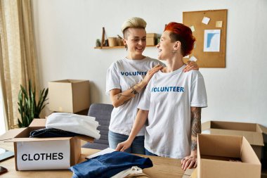Two women in volunteer t-shirts working together in a room. clipart