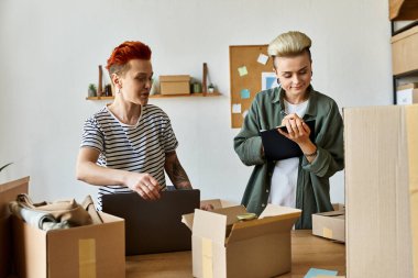 Genç lezbiyen çift bir odada kutuları düzenliyor, hayır işleri için birlikte çalışıyorlar..