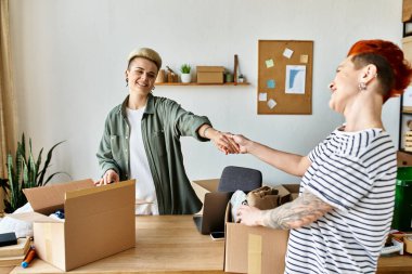 Two women shake hands in a room filled with donation boxes, united in their charitable efforts. clipart