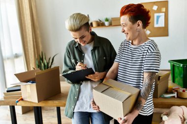 A young lesbian couple supports each other while doing charity work together. clipart