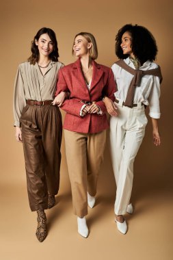 Üç genç, şık giyinmiş güzel kadın, dostluk ve kültürel çeşitliliğin gösterisinde sıcak bir gülümsemeyle yan yana duruyorlar..