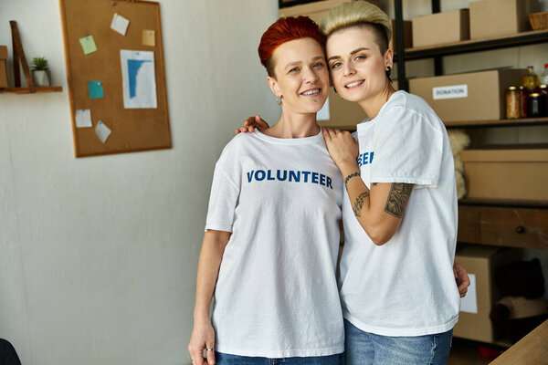Лесбийская пара в футболках-волонтерах объединяется в благотворительной деятельности, демонстрируя командную работу и солидарность.