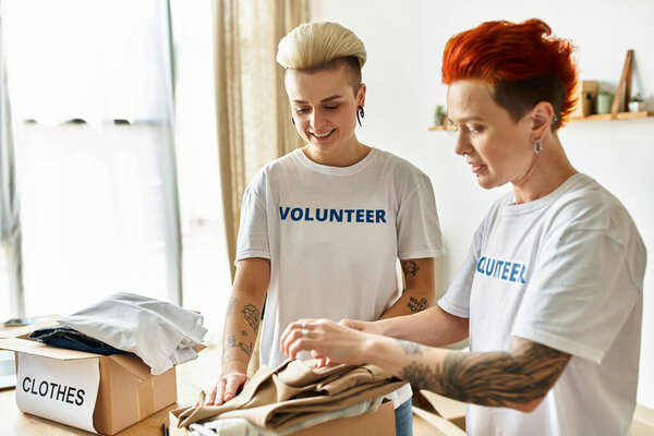 couple unpack clothes together in a room, wearing volunteer t-shirts, spreading love through charitable actions.