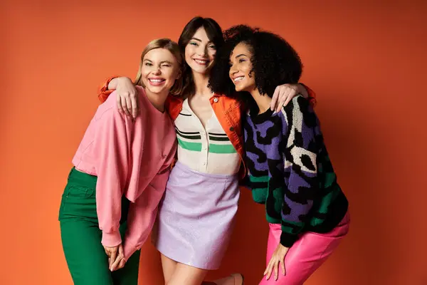 stock image Young, beautiful women in stylish clothes celebrating friendship and cultural diversity on an orange background.