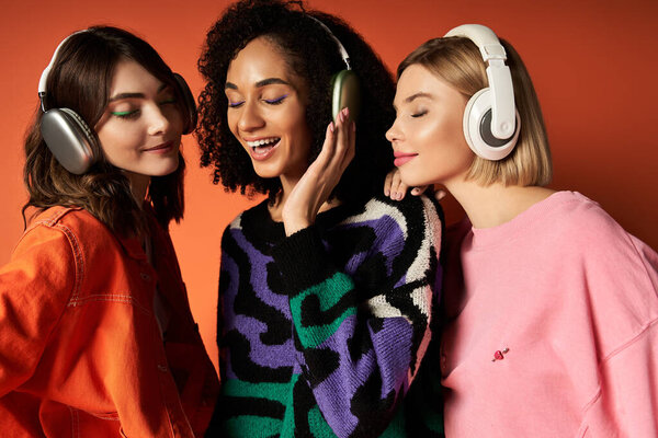 Three young women, dressed in vibrant clothes, wearing headphones and sharing a moment of connection and communication while looking at each other.