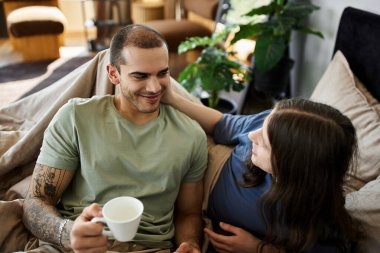 A young gay couple enjoys a cozy morning together in their bedroom. clipart