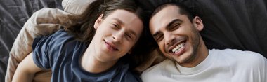 A young gay couple shares a tender moment in their bedroom, their faces illuminated with genuine joy and love. clipart