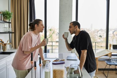 Genç eşcinsel bir çift modern mutfaklarında sabah kahvesinin tadını çıkarıyor..