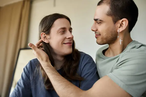 Stock image A young gay couple share a tender moment in their bedroom, gazing into each others eyes.