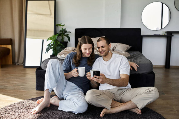 A young gay couple enjoys a relaxed morning together in their bedroom, sipping coffee and looking at smartphone