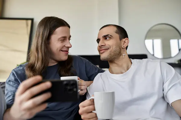 stock image A young gay couple shares a quiet moment together in their bedroom, enjoying each others company and a cup of coffee.