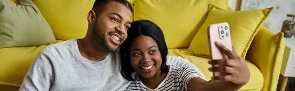 stock image A loving African American couple takes a selfie on a yellow couch.