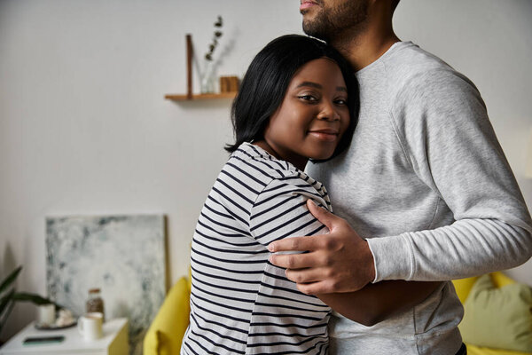 A couple embraces in their home, expressing their affection for each other.