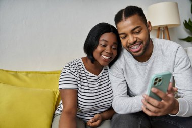 Afro-Amerikalı bir çift evdeki bir kanepede dinlenirken bir dakikalık ortak kahkahadan zevk alır..
