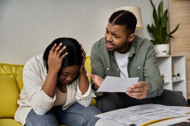 A couple argues over bills and finances while sitting on a couch. clipart