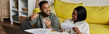 A loving African American couple laughs together at home. clipart