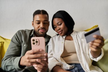 Afrikalı bir Amerikalı çift, internet üzerinden akıllı telefon ve kredi kartıyla alışveriş yapıyor..