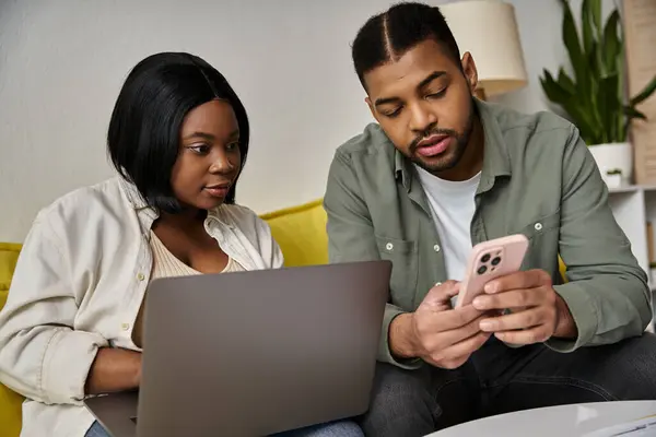 stock image A young African American couple relax at home with laptops and a phone.