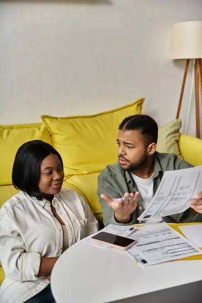 stock image A loving African American couple sits at a table, reviewing documents and discussing finances.
