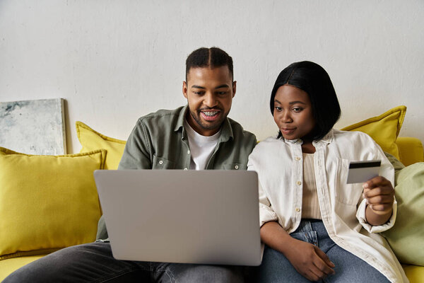 A loving couple shops online together while sitting on a couch.